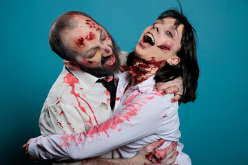 Brain eating halloween zombies hugging over blue background, acting aggressive and frightening....