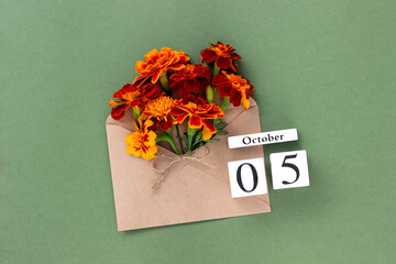 October 5. Bouquet of orange flower in craft envelope and calendar date on green background. Minimal concept Hello fall. Template for your design, greeting card