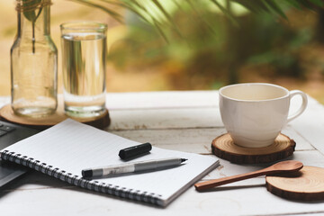 A notebook and pen were placed on the desk beside a white coffee mug.