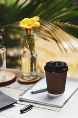 A hot coffee mug placed with a notebook with a pen.