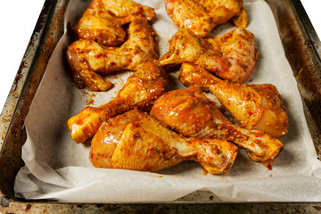 Corn fed chicken wings and drumstick in Asian style spicy marinated with herbs in a metal cooking tray. Close up. Uncooked chicken meat product for barbecue or frying. Isolated on white..