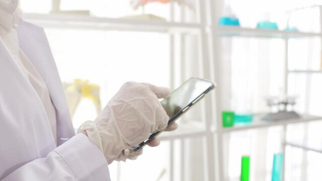 Hands of a pharmaceutical research scientist using smartphone to research medical research data laboratory : White researcher uses touchscreen smartphone to type and read text to enhance comprehension