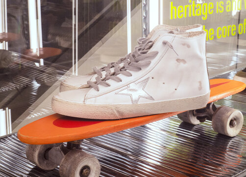 Golden Goose, luxury sneakers brand.High white shoes exposed on skateboard.Milan - Italy,03 September 2022