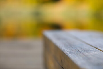 wooden bench in park close-up against background of yellow autumn leaves