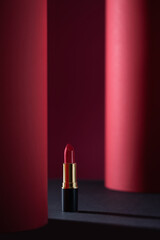 Red lipstick on creative red and black background. Still life of glamour lipstick, decorative cosmetics.