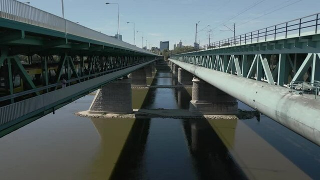 Unusual drone shot of a multi-storey bridge, with train and car traffic terminating on the Warszawa skyline
