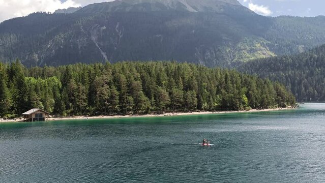 People Stand up Paddle board on a Lake Blindsee in the Mountains in Austria Tyrol, Hut by the Lake in background