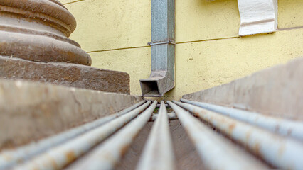 Metal rain drain at the base of the building.Very soft focus