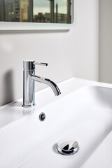 Bathroom interior modern design sink under mirror with window reflection. Interior of bathroom with washbasin and faucet elongated rectangular shape bowl.