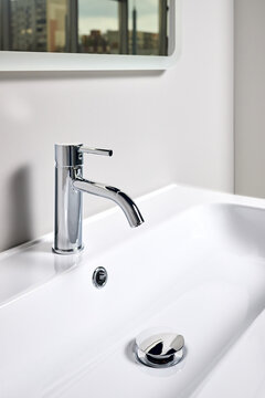 Bathroom interior modern design sink under mirror with window reflection. Interior of bathroom with washbasin and faucet elongated rectangular shape bowl.