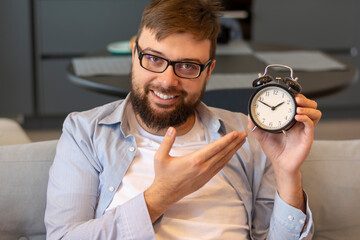 Holding a clock black mechanical in his hands successful man smiling with white teeth in glasses in...