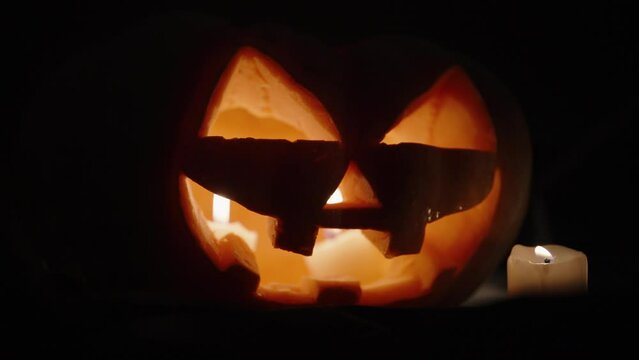 Pumpkin for Halloween, candles are burning inside. the camera's focus is slowly focused on her