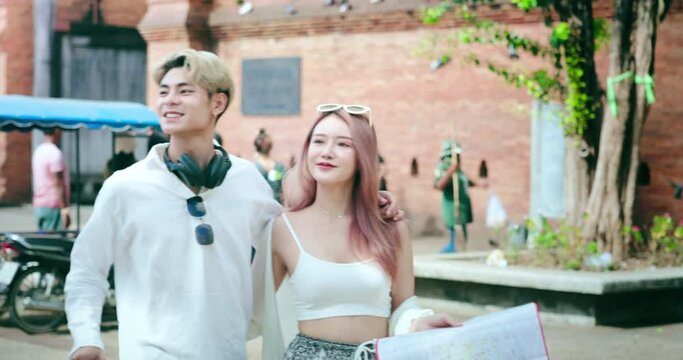 Tourist, asian people walking at Tha Phae Gate or Pratu Tha Pae. Landmark in Chiang Mai city of Thailand. To tour, travel, visit with information guide or map. Concept of tourism, attractions, couple.