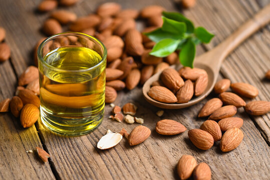 Almond oil and Almonds nuts on wooden, Delicious sweet almonds oil in glass, roasted almond nut for healthy food and snack organic vegetable oils for cooking or spa