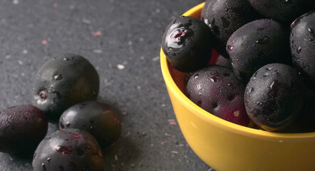 Jambul or Jamun (Syzygium cumini) in yellow bowl isolated on textured background.