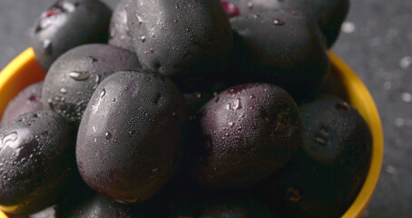 Jambul or Jamun (Syzygium cumini) in yellow bowl isolated on textured background.