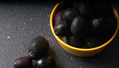 Jambul or Jamun (Syzygium cumini) in yellow bowl isolated on textured background.