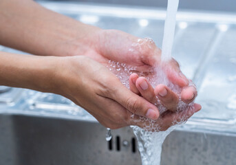 Fototapeta premium Woman is washing her hands with foam soap and clean water. Woman washing hands with soap in sink for prevent the spread of viral