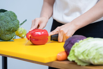 Young woman cutting vegetables in the kitchen. Woman's hands cutting vegetables, behind fresh vegetables. asian woman uses a knife and cooks.