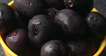 Jambul or Jamun (Syzygium cumini) in yellow bowl isolated on textured background.
