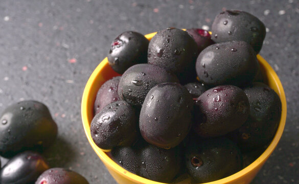 Jambul or Jamun (Syzygium cumini) in yellow bowl isolated on textured background.