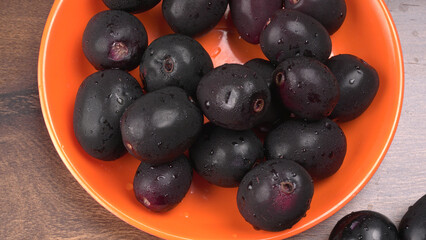 Jambul or Jamun (Syzygium cumini) in yellow bowl isolated on textured background.