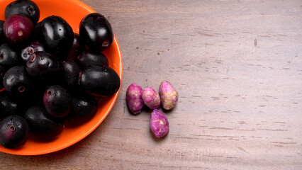 Jambul or Jamun (Syzygium cumini) in yellow bowl isolated on textured background.