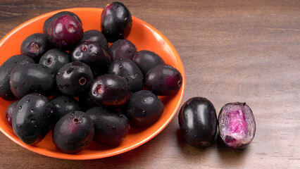 Jambul or Jamun (Syzygium cumini) in yellow bowl isolated on textured background.
