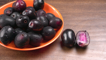 Jambul or Jamun (Syzygium cumini) in yellow bowl isolated on textured background.