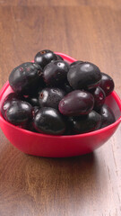 Jambul or Jamun (Syzygium cumini) in yellow bowl isolated on textured background.