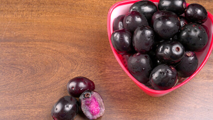 Jambul or Jamun (Syzygium cumini) in yellow bowl isolated on textured background.