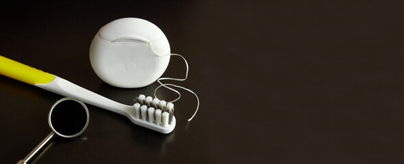 Dental mirror, dental floss and toothbrush on a black background. Dental care.