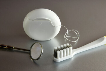 Dental mirror, dental floss and toothbrush on gray background. Dental king.