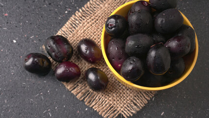 Jambul or Jamun (Syzygium cumini) in yellow bowl isolated on textured background.