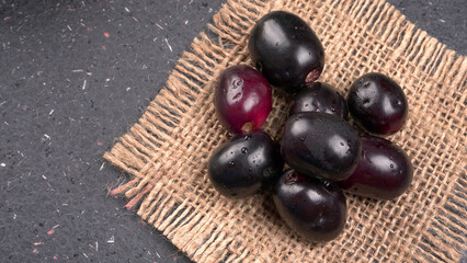 Jambul or Jamun (Syzygium cumini) in yellow bowl isolated on textured background.