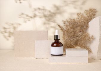 Brown dropper cosmetic bottle with blank label on stones near pampas grass close up, Mockup