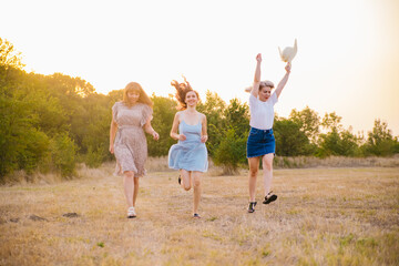 Fototapeta premium A group of girlfriends jumps and runs outdoors. A group of female friends hugs and enjoys the sunset in nature. Laughter, smiles and joy.