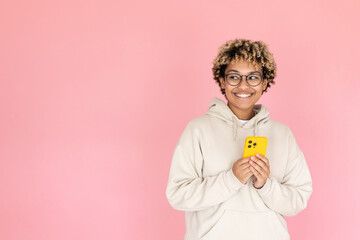 Smiling African American woman with phone. Female model in glasses with curly hair holding mobile phone in studio. Portrait, studio shot, emotion concept