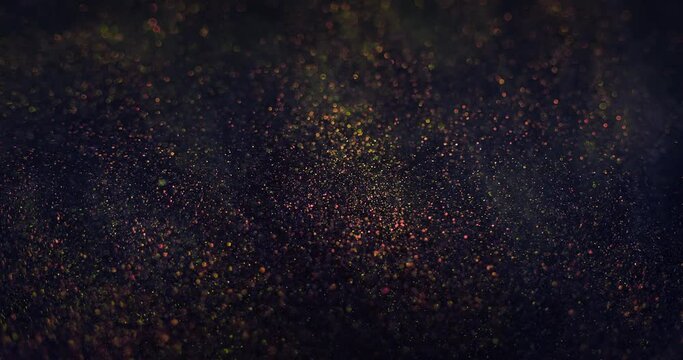 Glitter splash. Particles background. Bokeh sparks. Defocused purple bronze golden color grain floating on dark night abstract vertical texture. Shot on RED Cinema camera.