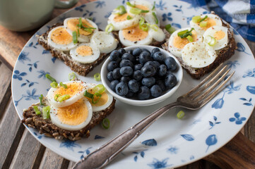 Fitness breakfast  sandwich with boiled eggs, chives and fresh blueberries