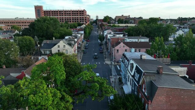 Reverse dolly above city street in downtown area. American town during late afternoon, early evening light.