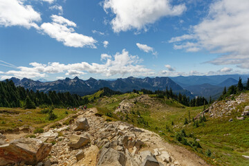 Fototapeta na wymiar The skyline trail surrounded by a landscape of mountains, forests, and a cloudy blue sky at Mt. Rainier National Park.