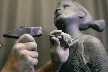 Man sculptor creates sculpt bust human woman sculpture with hammer. Statue craft creation workshop. - obrazy, fototapety, plakaty