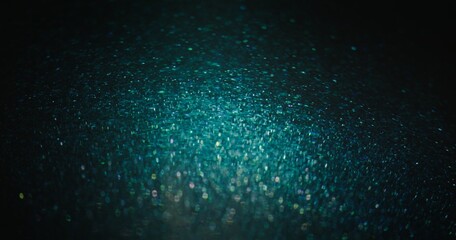 Blur sparkles background. Glitter particles. Shimmering bokeh glow. Defocused blue green color grain glare on dark black abstract poster.