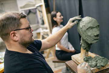 Man sculptor creates sculpt bust clay human woman sculpture. Statue craft creation workshop.