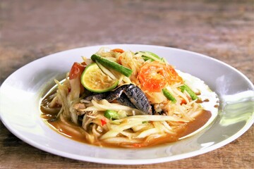 Famous Thai food papaya salad with dried shrimp and salted crab on white plate photo on wooden back ground