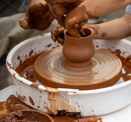 The potter teaches a young student.