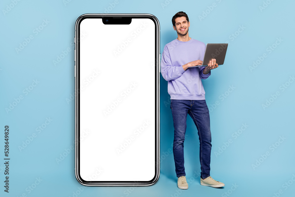 Poster full length body size view of handsome guy using laptop near big device copy space ad isolated over 