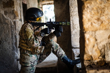 A woman in an army uniform shoots a firearm in an abandoned building. 