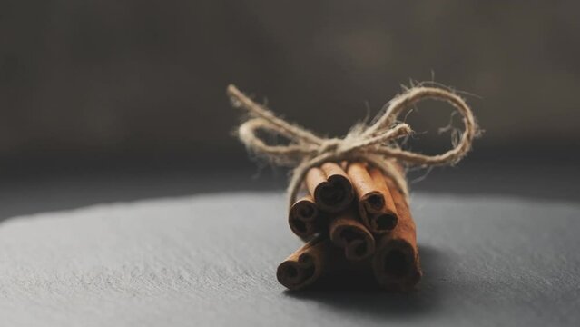 Dried cinnamon rolled in sticks and tied with rope on dark background